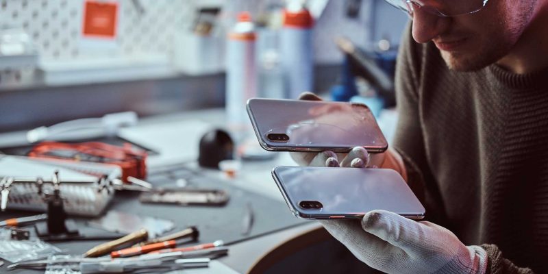 technician-holds-two-identical-smartphones-for-com-KBP99A4.jpg